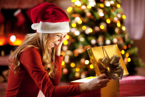 Ecstatic woman opening Christmas presents.